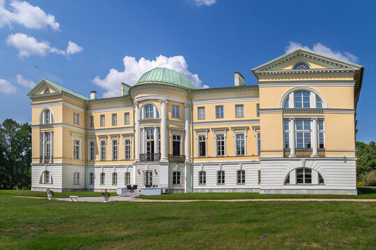 Rear facade view of Mezotne Palace in Latvia featuring a rotunda. Classicism architecture under a clear blue sky