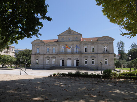 View of the Deputacion Provincial de Pontevedra Pazo Provincial, a grand neoclassical stone building with flags displayed on the facade, situated in a park in Pontevedra, Pontevedra, Spain.