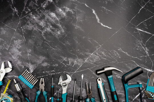 Assorted Hand Tools Laid Out on black marble background, top view with space for text