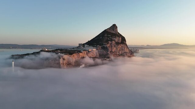 Aerial view of the Rock of Gibraltar rising above a dense sea of clouds with the Europa Point lighthouse visible in the foreground, Gibraltar, Gibraltar.