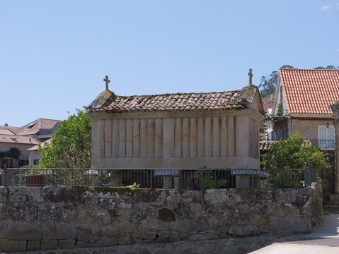 View of a traditional stone horreo granary with a tiled roof and stone pillars in the historic village of Combarro, Pontevedra, Spain.
