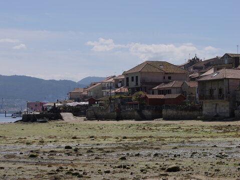 View of the historic fishing village of Combarro with traditional stone houses and granaries along the rocky waterfront at low tide in Combarro, Pontevedra, Spain.