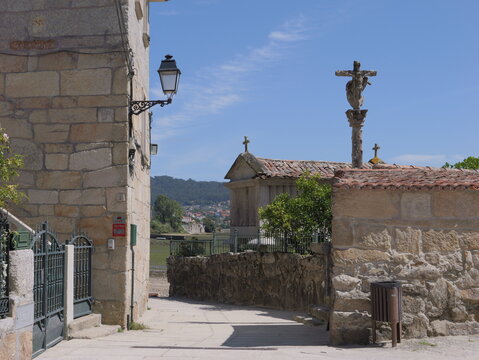 View of the historic stone horreos and traditional stone cross in the coastal village of Combarro, Pontevedra, Spain.