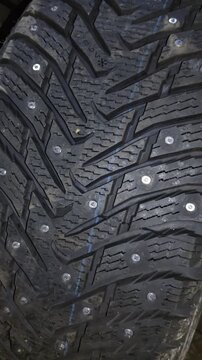 Close-up view of winter tire tread pattern featuring snowflake symbol and metal studs
