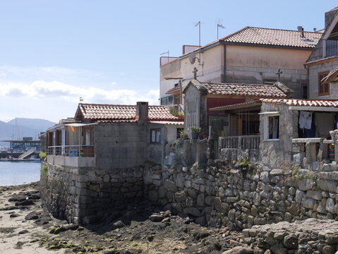 View of traditional stone houses and historic granaries along the rocky coastline in the coastal village of Combarro, Pontevedra, Spain.