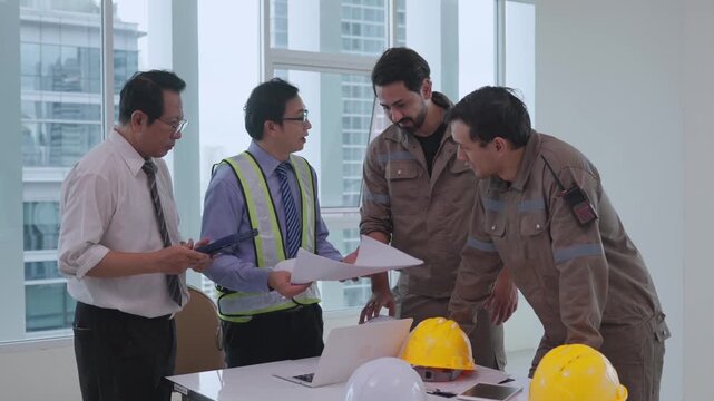 Construction worker team collaboration and discussion with engineer supervisor reviewing building plan, safety helmet office table, focused construction project planning meeting modern workplace with