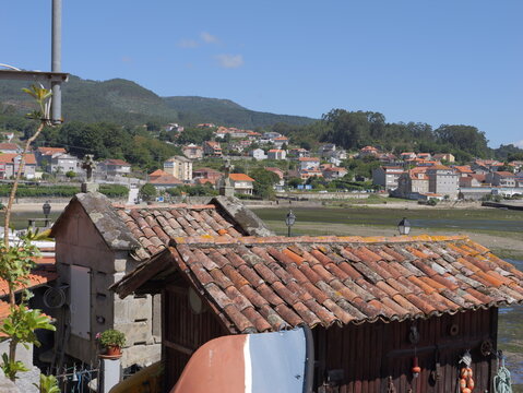 View of traditional stone horreos with terracotta tiled roofs overlooking the coastal village of Combarro, Pontevedra, Spain.