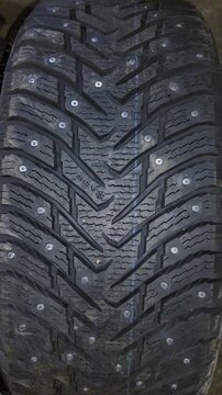 Close-up of a truck tire tread with embedded studs and deep grooves