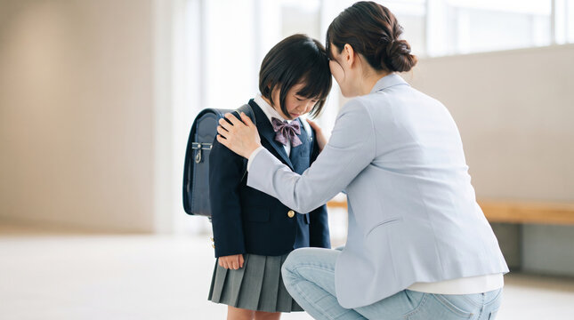 泣いている新小学生の子供を優しく慰める母親