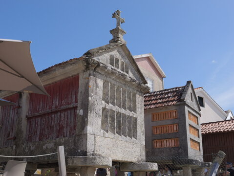 View of traditional stone horreos with red wooden doors and stone crosses in the historic village of Combarro, Pontevedra, Spain.