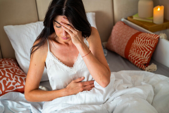 Woman sitting in her bed with stomach pain