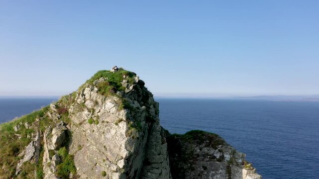 Aerial view of Tormore Island sea stack with rugged cliffs and green slopes rising from the Atlantic Ocean in Ardara, County Donegal, Ireland.
