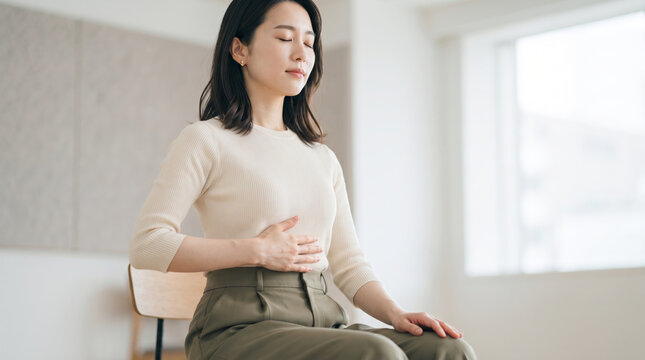 目を閉じて深呼吸を行い心をリラックスさせる女性