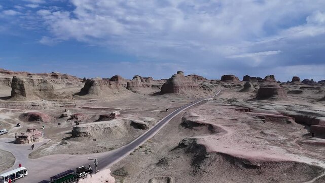 A road winding through the "Devil's City" in the Urho District of Karamay, Northern Xinjiang, China&mdash;a landscape of rocky desert terrain featuring strange formations resembling towers and animals.
