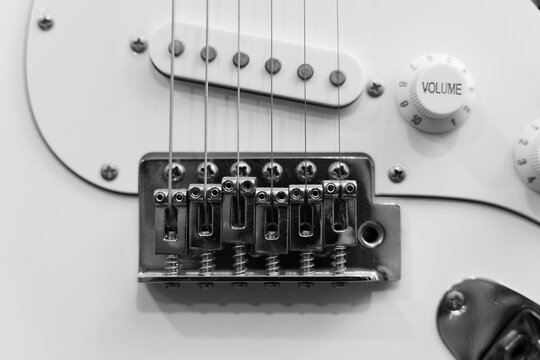 Closeup view of electric guitar bridge and strings. Black and white.