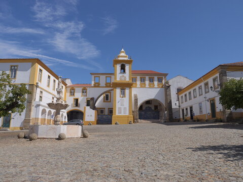 View of the historic Saint Bernard Convent with its distinctive yellow and white facade, stone fountain, and cobblestone square in Portalegre, Portalegre District, Portugal.