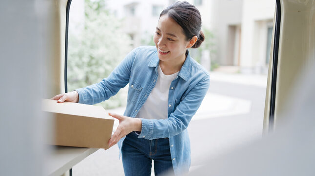 車から荷物を積み下ろしする笑顔の女性ドライバー