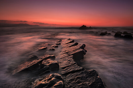 Long exposure sunset over flysch rock formations at Barrika beach Basque Country Spain, dramatic sky and motion sea background