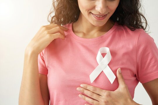 Woman wearing a pink tshirt with a white awareness ribbon isolated on white background