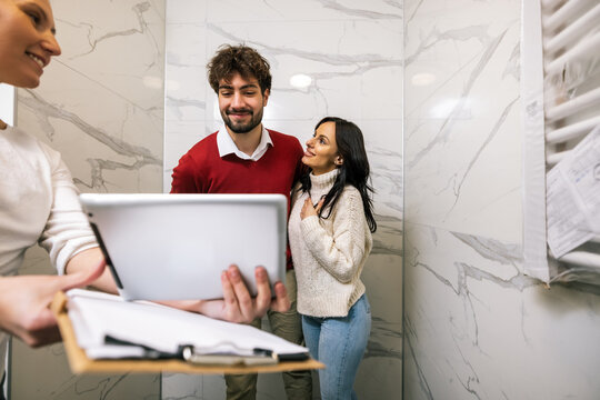 Real estate agent showing digital tablet presentation to young couple