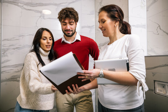 Young couple reviewing contract documents with real estate agent in apartment