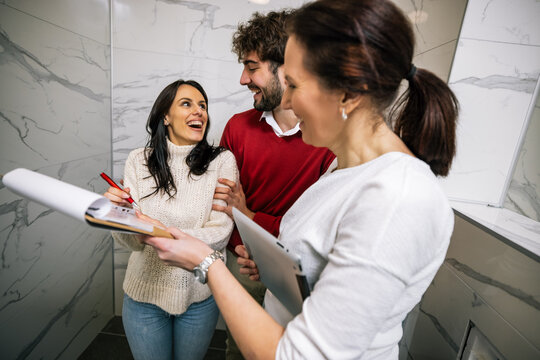 Happy woman holding pen and contract laughing with partner and realtor