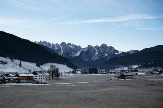 Wide landscape shot of Gosau village surrounded by snow covered Gosaukamm alpine peaks and pine forest in winter. Alpine village in Salzkammergut, Austria.