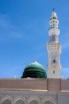 View of the iconic green dome and tall white minaret of Al Masjid-e-Nabawi against a clear blue sky in Madinah, Al Madinah Province, Saudi Arabia.