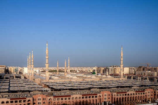 View of Al Masjid-e-Nabawi with its iconic minarets and expansive courtyards under a clear blue sky in Madinah, Al Madinah Province, Saudi Arabia.