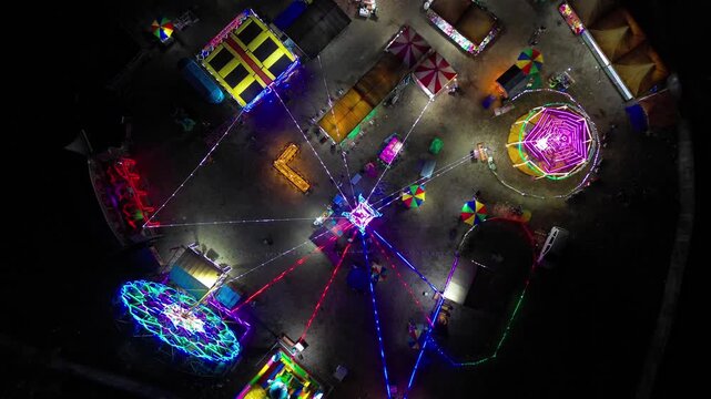 Aerial view of a vibrant night carnival with illuminated rides, colorful lights, and bustling activity at the fairground in Mataram, West Nusa Tenggara, Indonesia.