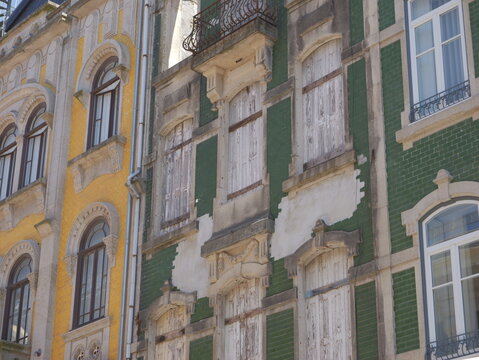 View of historic buildings featuring traditional colorful tiles and weathered wooden shutters in the city center of Porto, Porto District, Portugal.