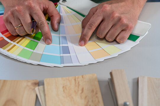 Close up of Interior Designer Choosing Color Swatch Palette Fan and Wood Finish Samples