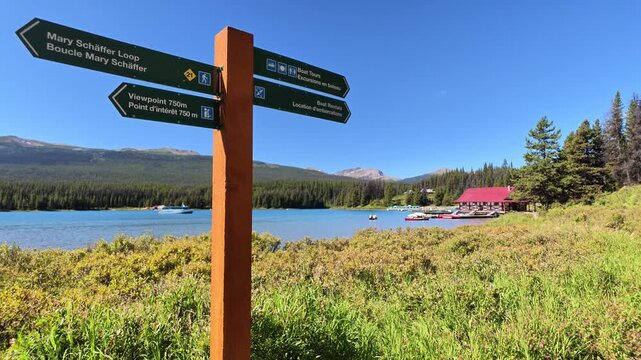 Maligne Lake's turquoise waters mirror the Rockies, with a boathouse, boat tours and rentals, and a trail sign guiding hikers around this iconic Jasper National Park viewpoint in Alberta of Canada