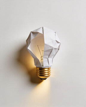Origami paper lightbulb displaying conceptual minimalism as metaphor for fresh startup idea and bright insight.