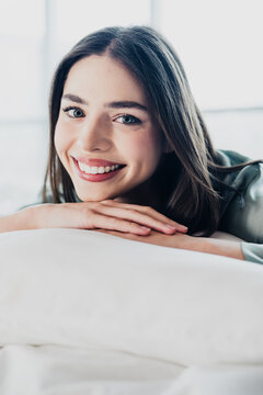 Smiling young woman relaxed on bed close-up portrait with natural light and friendly expression