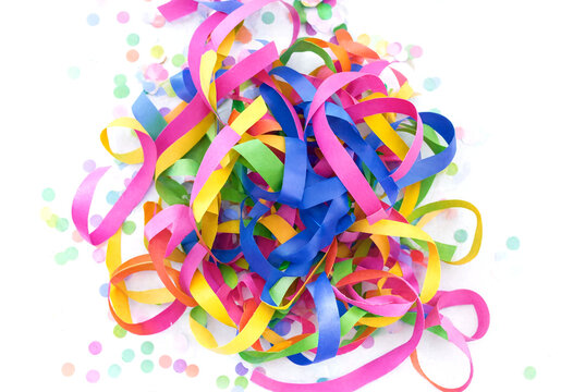 Colorful celebration streamers scattered with confetti on light background