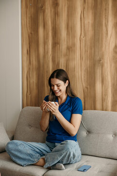 Woman relaxing at home, enjoying a coffee on sofa