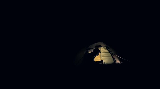 A man eating camping food inside a tent at night