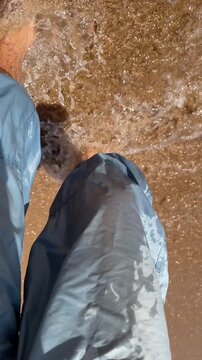 Barefoot person wading through shallow surf