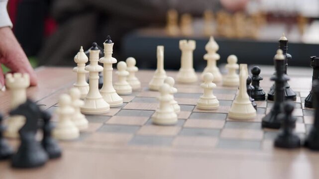 Low-angle closeup of fingertip hovering above white pawn on checkered chessboard on wood table surface, focused midgame move before contact