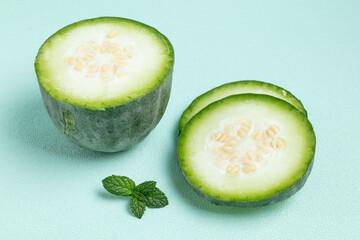 Sliced Green Melon with Mint Leaves on Blue Background © HoangNgoc