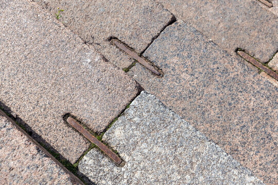 Weathered stone steps with iron anchor fittings, top view showing textured granite surfaces, wear and historic urban character ideal for architectural, heritage, and backgrounds