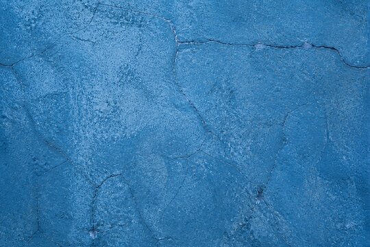 Blue cracked plaster showing rough wall texture close up background