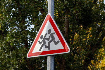 Warning sign indicating children playing in a residential area near trees during the day © Sasha