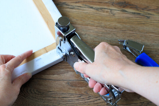Canvas stretching with a metal staple gun fixing canvas material to a wooden stretcher bars