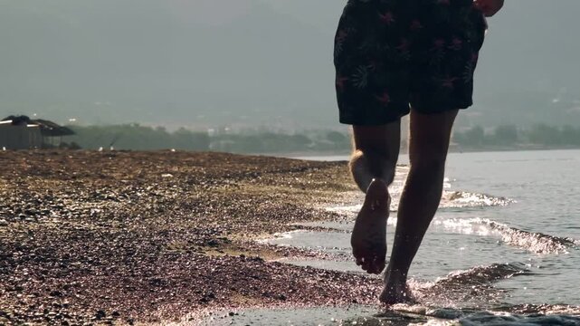A slow motion video of an eight year old female one eyed pitbull running together with her athletic forty year old male owner on a sunny morning sandy beach.