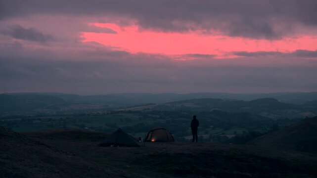 A man and two tents in the hills at dawn