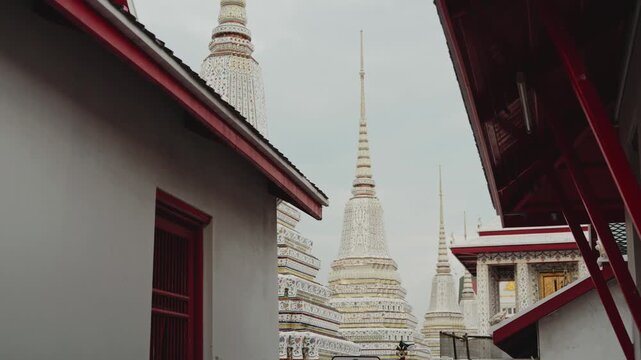 Famous wat pho temple with its iconic white and gold pagodas under an overcast sky in bangkok