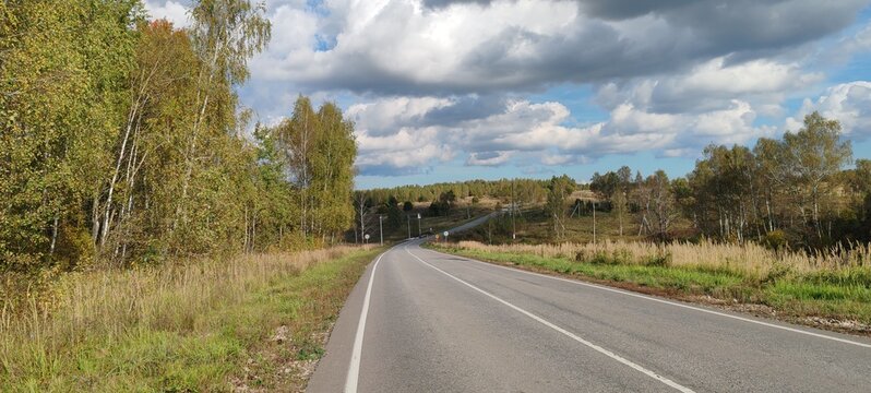 Autumn country road leading toward blue sky near Tula
