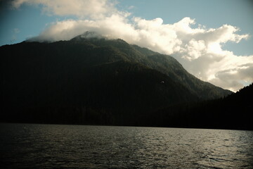 Obraz premium Clouds wrapping a dark mountain above a wide lake